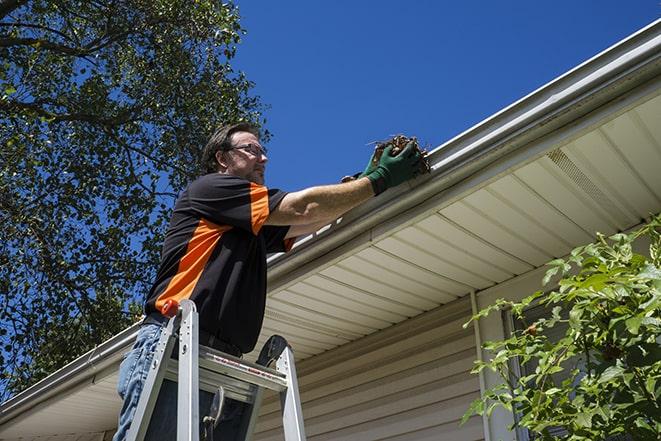 skilled laborer conducting repairs on a house's gutter in Commerce, CA